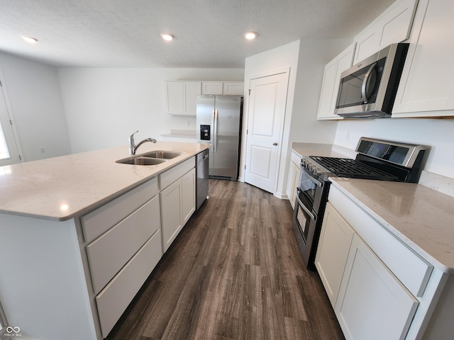 kitchen with an island with sink, appliances with stainless steel finishes, dark wood-type flooring, white cabinetry, and a sink