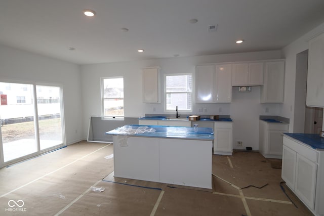 kitchen featuring a center island, sink, and white cabinets