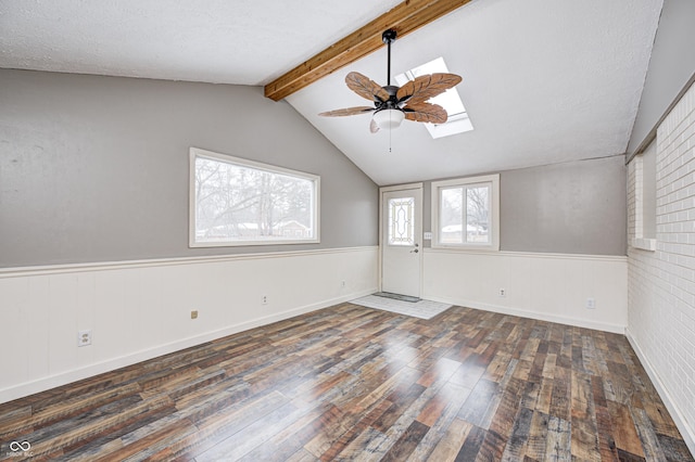 spare room featuring ceiling fan, vaulted ceiling with skylight, dark wood-type flooring, and a textured ceiling