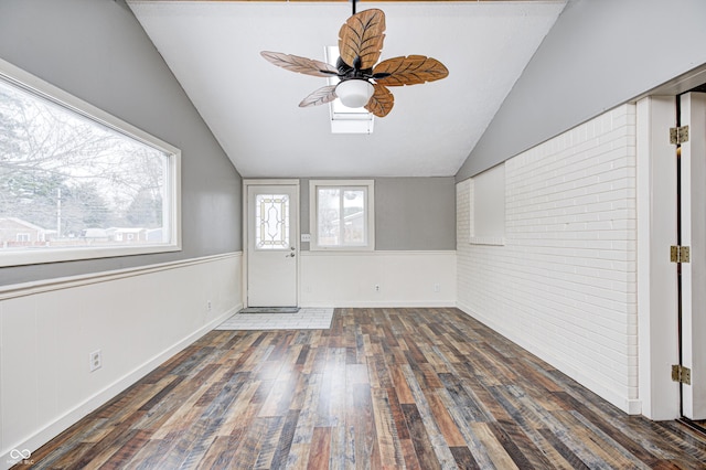 foyer with ceiling fan, vaulted ceiling, dark hardwood / wood-style flooring, and brick wall