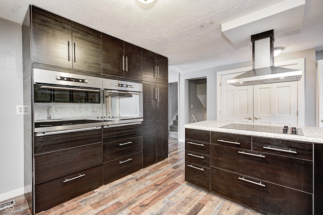 kitchen with dark brown cabinetry, black electric stovetop, island exhaust hood, and a textured ceiling