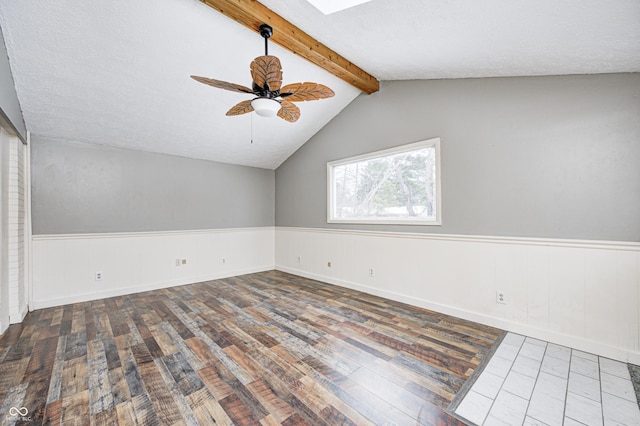 spare room featuring ceiling fan, a textured ceiling, wood-type flooring, and vaulted ceiling with beams