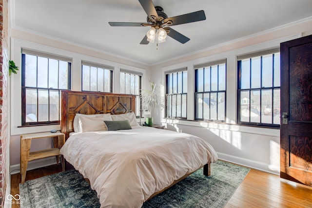 bedroom featuring ceiling fan, light hardwood / wood-style floors, multiple windows, and ornamental molding