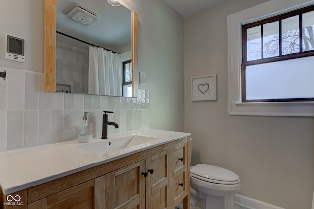 bathroom with toilet, a healthy amount of sunlight, backsplash, and vanity