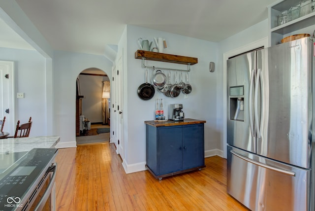 kitchen featuring light hardwood / wood-style floors, stainless steel fridge, wooden counters, and blue cabinets