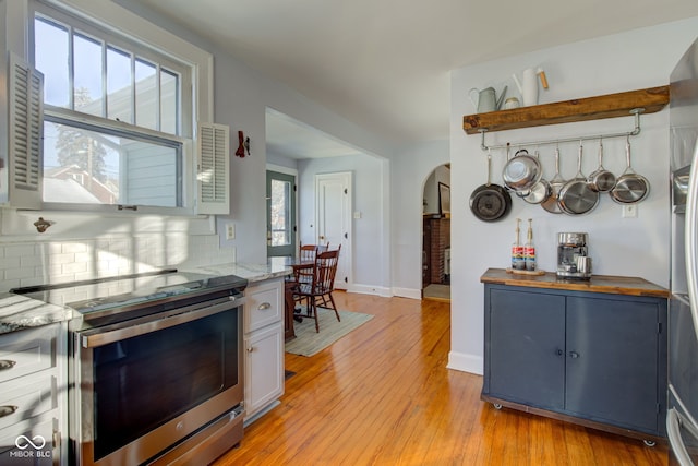 kitchen featuring stainless steel range with electric stovetop, butcher block counters, tasteful backsplash, blue cabinets, and white cabinets