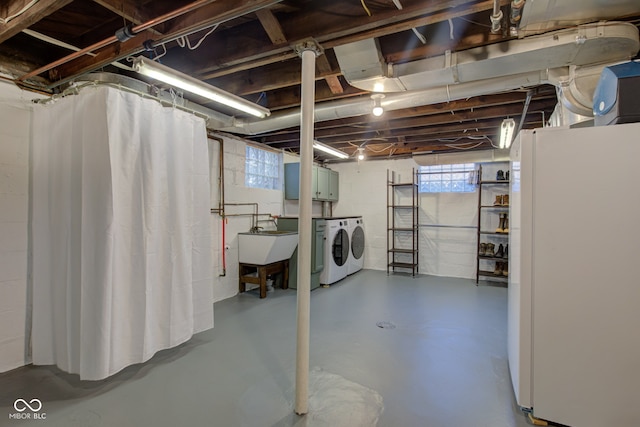 basement featuring washer and dryer, sink, and white fridge