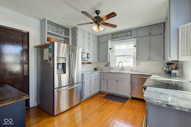 kitchen featuring appliances with stainless steel finishes, tasteful backsplash, light hardwood / wood-style floors, sink, and gray cabinetry