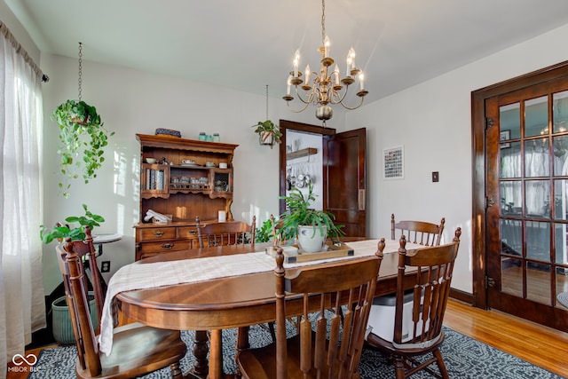 dining space with hardwood / wood-style floors and an inviting chandelier