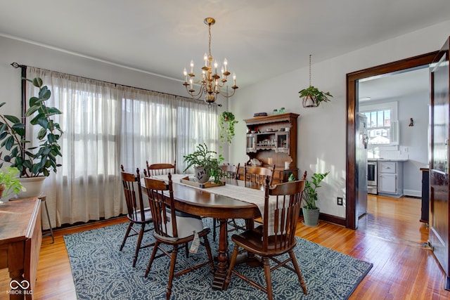 dining space with light hardwood / wood-style flooring and a chandelier