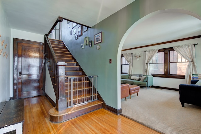 staircase featuring ornamental molding and hardwood / wood-style flooring