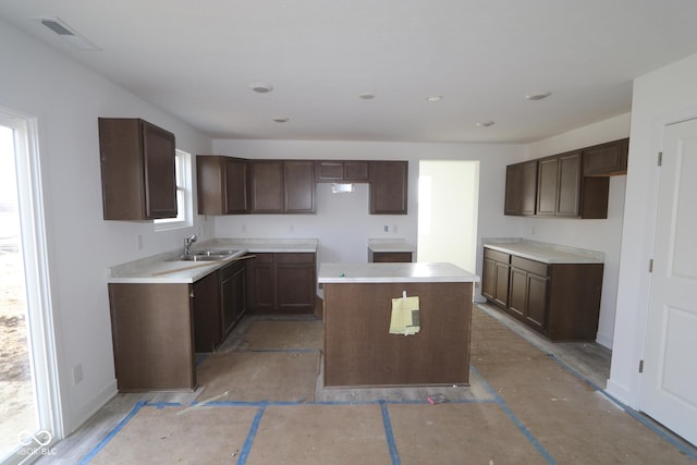 kitchen featuring dark brown cabinetry, a center island, and sink