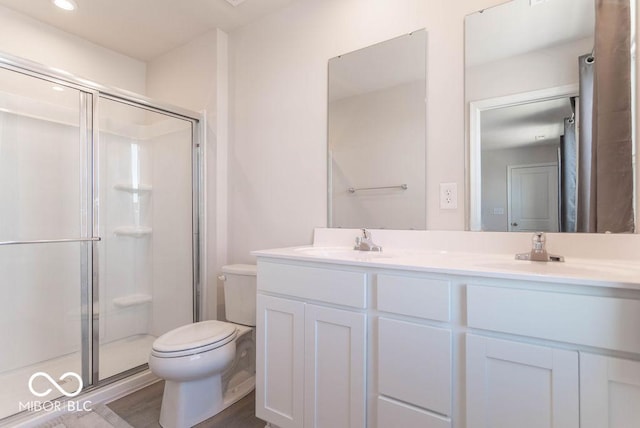 bathroom featuring hardwood / wood-style floors, toilet, walk in shower, and vanity