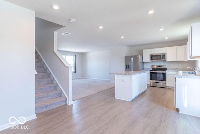 kitchen featuring white cabinets, a center island, light hardwood / wood-style flooring, and stainless steel appliances