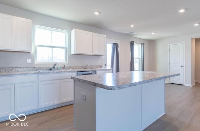 kitchen with white cabinets, a center island, light hardwood / wood-style flooring, and sink