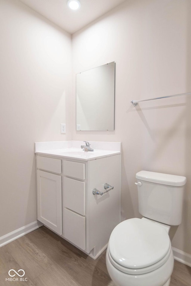 bathroom with hardwood / wood-style floors, toilet, and vanity