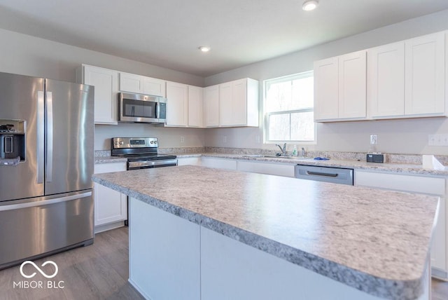 kitchen featuring appliances with stainless steel finishes, white cabinetry, sink, a kitchen island, and dark wood-type flooring