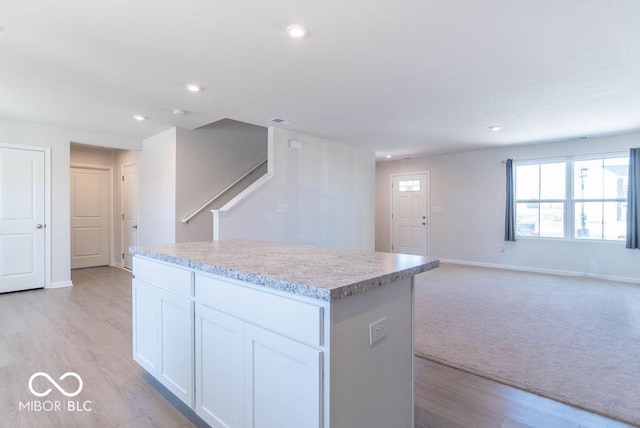 kitchen with white cabinets, a center island, and light hardwood / wood-style flooring