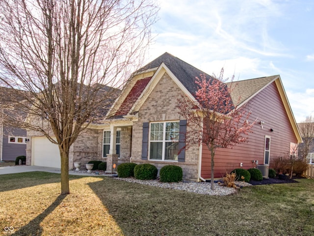 craftsman-style home featuring brick siding, a shingled roof, a front yard, driveway, and an attached garage