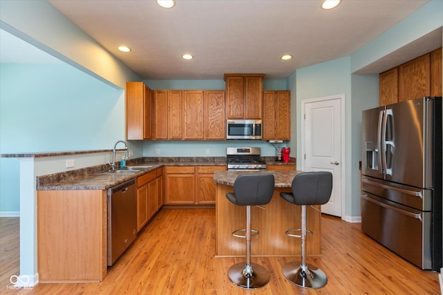 kitchen featuring sink, a breakfast bar area, stainless steel appliances, a center island, and light wood-type flooring