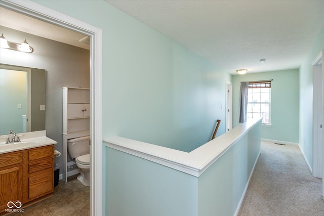 corridor with sink and light colored carpet