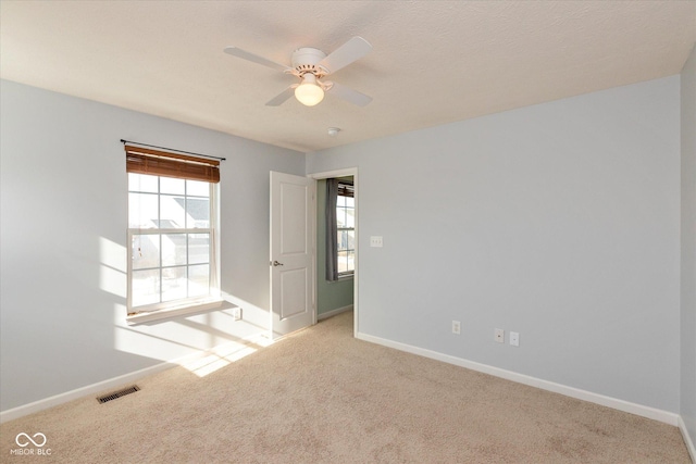 empty room with ceiling fan and light carpet