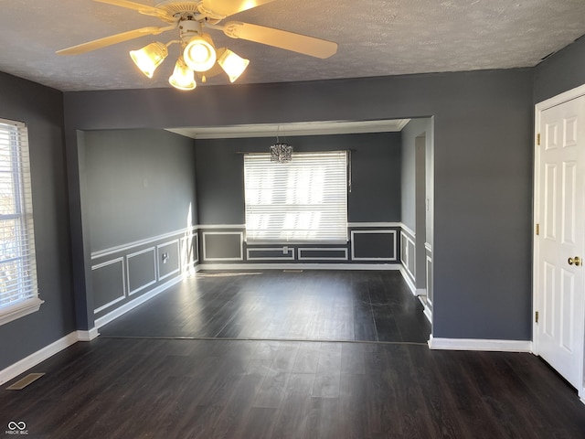 unfurnished room with ceiling fan with notable chandelier, a textured ceiling, and dark hardwood / wood-style floors