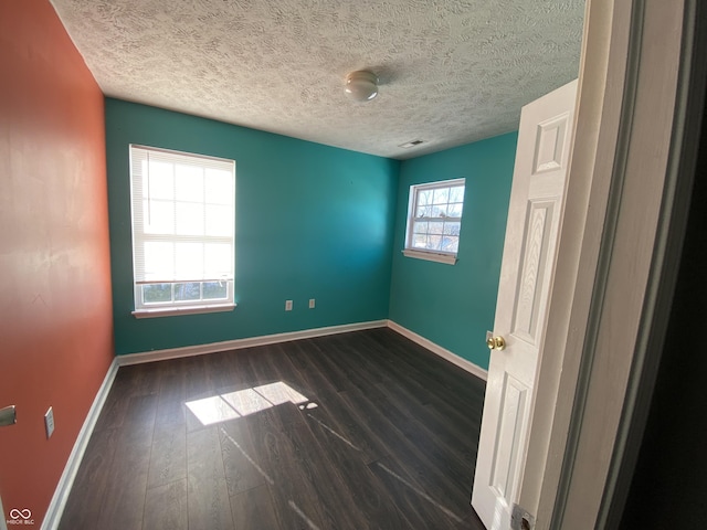 spare room with a textured ceiling and dark hardwood / wood-style flooring