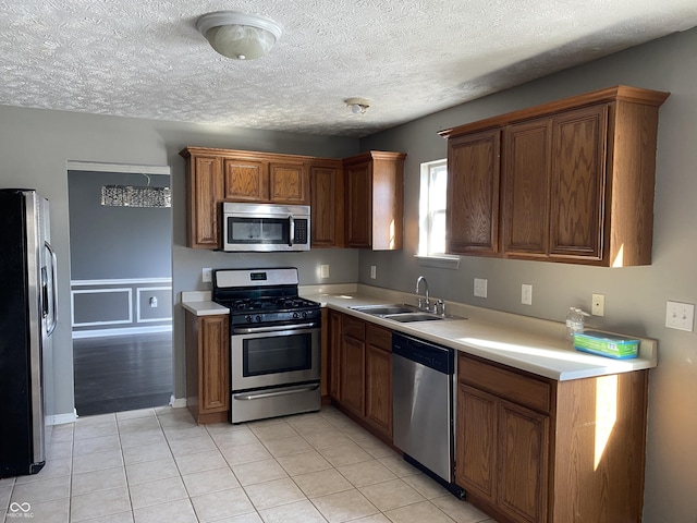 kitchen featuring light tile patterned floors, appliances with stainless steel finishes, sink, and a textured ceiling