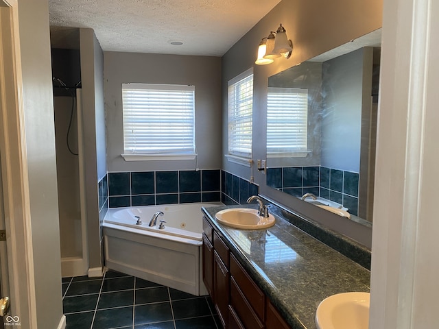 bathroom with a textured ceiling, tile patterned floors, vanity, and a bath