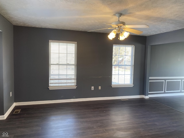 spare room with ceiling fan, plenty of natural light, a textured ceiling, and dark hardwood / wood-style floors