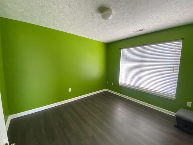 empty room featuring dark wood-type flooring and a textured ceiling