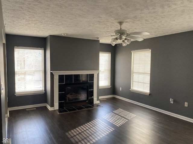 unfurnished living room featuring a textured ceiling, ceiling fan, dark hardwood / wood-style flooring, and a tile fireplace