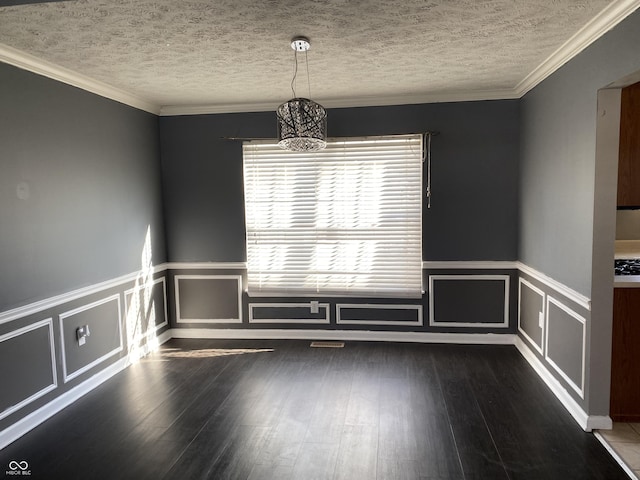 unfurnished room featuring a textured ceiling, dark wood-type flooring, ornamental molding, and a notable chandelier