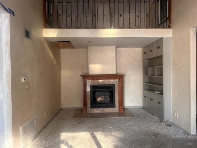 208 Winding Dr, Alexandria, IN 46001 - unfurnished living room with a high ceiling, built in shelves, a premium fireplace, and light colored carpet