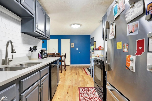 kitchen featuring sink, gray cabinetry, light hardwood / wood-style flooring, stainless steel appliances, and backsplash