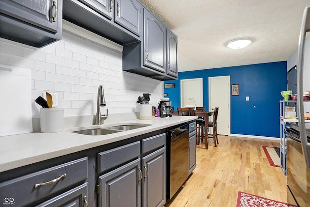 kitchen with light hardwood / wood-style floors, black dishwasher, sink, and decorative backsplash