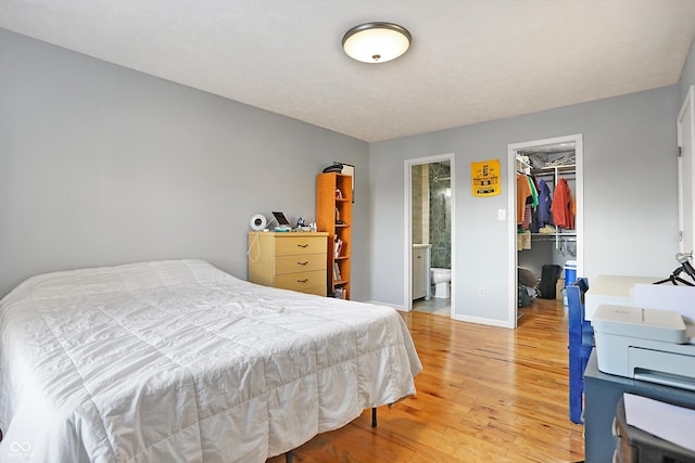 bedroom with hardwood / wood-style flooring, a walk in closet, a closet, and ensuite bathroom