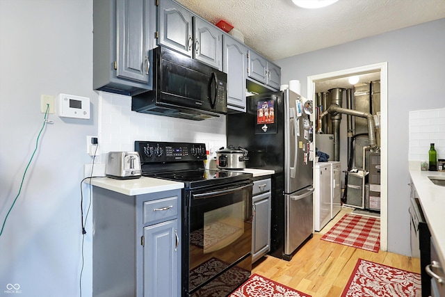 kitchen with tasteful backsplash, independent washer and dryer, black appliances, a textured ceiling, and light wood-type flooring