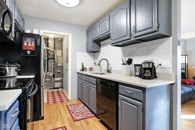 kitchen with sink, black appliances, light hardwood / wood-style floors, and a textured ceiling