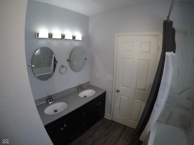 bathroom with wood-type flooring, a textured ceiling, vanity, and shower / tub combo with curtain