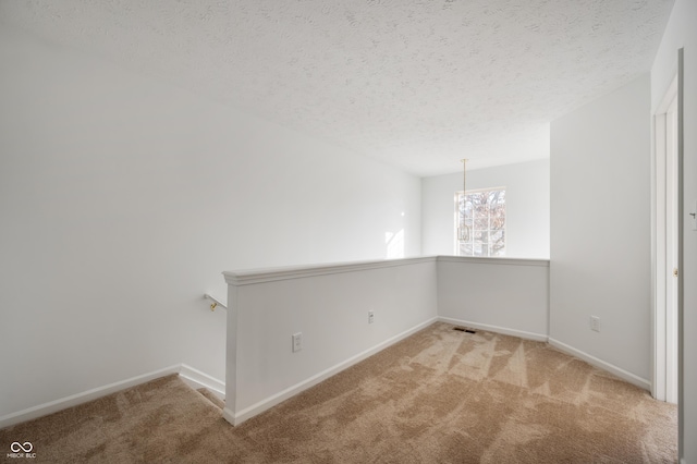 unfurnished room with light colored carpet and a textured ceiling