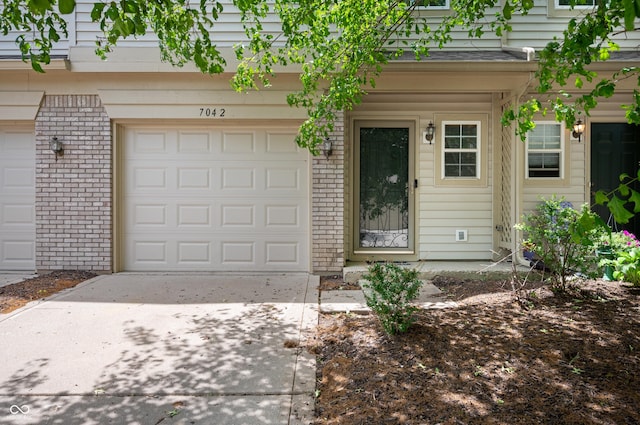 7042 Tyler Ln, Indianapolis, IN 46217 - doorway to property featuring driveway, a garage, and brick siding