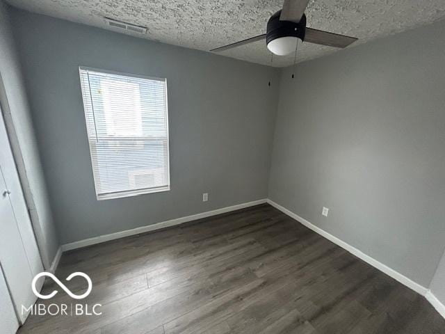 unfurnished room with a textured ceiling, dark hardwood / wood-style floors, and ceiling fan