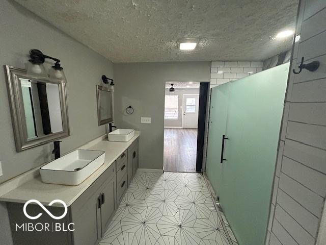 bathroom with vanity, ceiling fan, an enclosed shower, and a textured ceiling