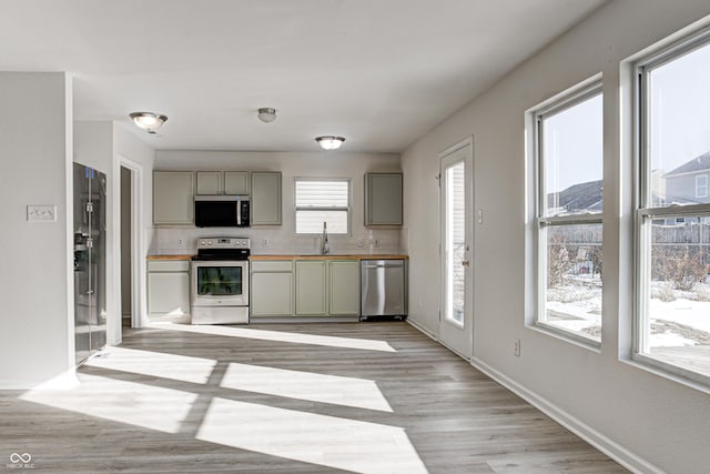 kitchen with backsplash, wooden counters, sink, and stainless steel appliances