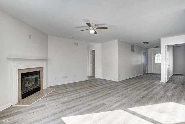 unfurnished living room with ceiling fan, light wood-type flooring, and a high end fireplace