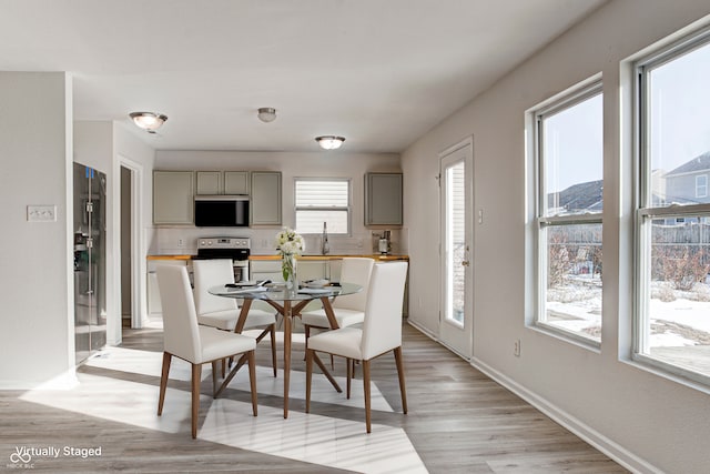 dining area with plenty of natural light, sink, and light hardwood / wood-style floors