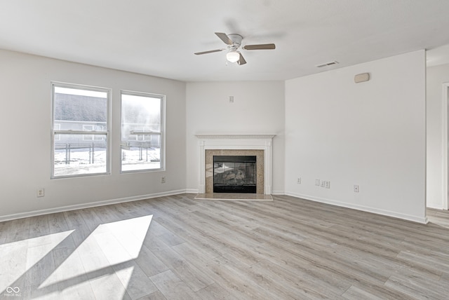 unfurnished living room with ceiling fan, a fireplace, and light hardwood / wood-style flooring