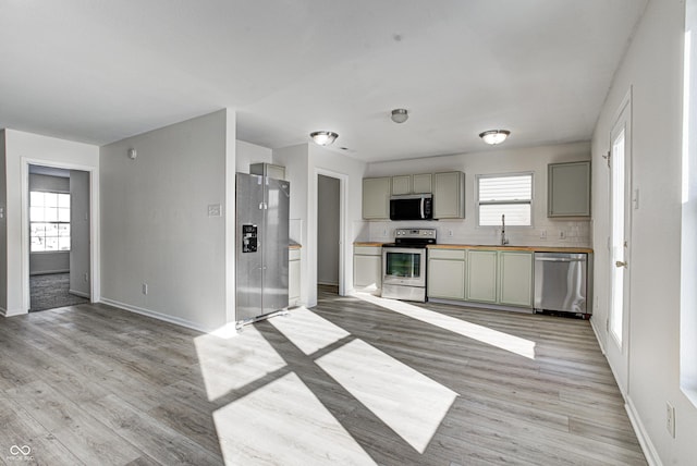 kitchen with light hardwood / wood-style floors, decorative backsplash, sink, gray cabinetry, and stainless steel appliances